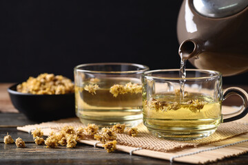 Chrysanthemum flower hot tea in teapot and pouring into a cup glass, Healthy Herbal drink