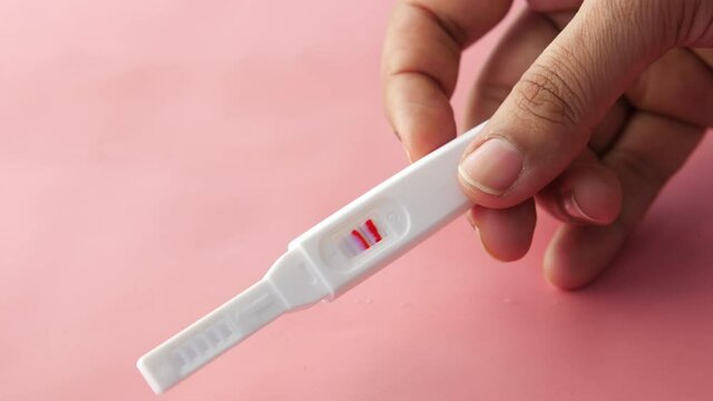 hand holding Pregnancy test kit on pink 