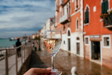 Venice and wine lover with wineglass in a hand. Drinking wine at embankment with old houses of...