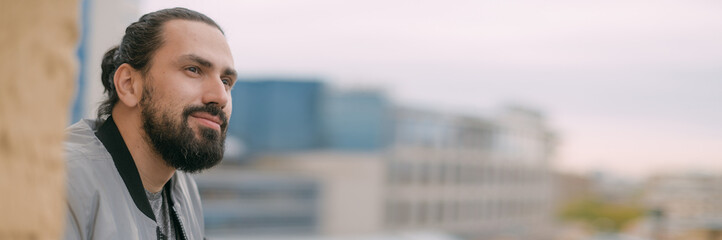 Fototapeta premium Portrait of a young handsome man on the balcony overlooking the city. City life.