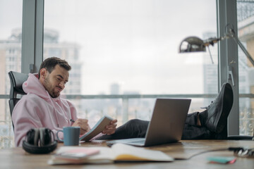 Fototapeta premium A young, serious man works hard alone in the office at a laptop.