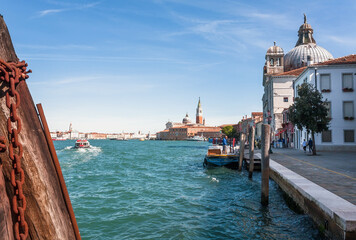 Water of lagoon near island of Giudecca with churches and historical mansions under blue sky