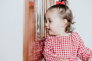 close up portrait of beautiful baby girl at home looking by window door. One year old girl. Lifestyles indoor