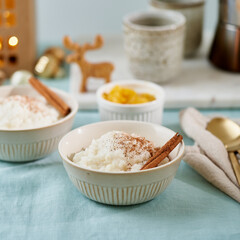 Christmas food. Rice pudding. Pastel cozy atmosphere morning holiday breakfast or evening lunch. Christmas decoration in living dinning room. Side view