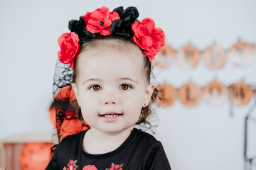 portrait of beautiful one year old caucasian girl in halloween costume at home with Halloween decoration, Lifestyle indoors. Halloween party concept.