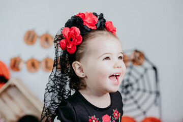 close up of beautiful one year old caucasian girl in halloween costume smiling at home with Halloween decoration, Lifestyle indoors. Halloween party concept.