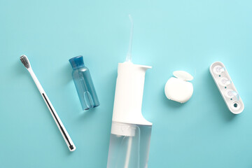 Oral water irrigator, toothbrush, liquid, flosser on blue background. Flat lay, top view, overhead.