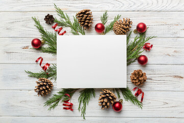 Fototapeta na wymiar Flat lay Christmas composition. square Paper blank, pine tree branches, christmas decorations on Colored background. Top view, copy space for text