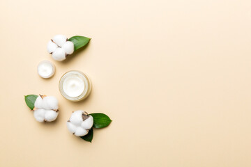 Organic cosmetic products with cotton flower and green leaves on color background. Copy space, flat lay