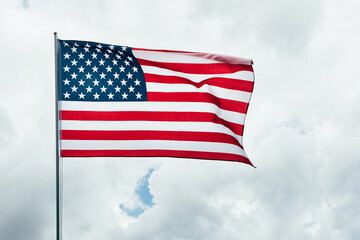 Obraz premium USA America flag waving in the wind over cloudy sky low angle view close up.