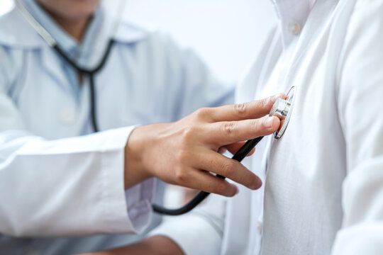Cropped image of male doctor's hand using stethoscope to examining heartbeat and symptom of patient while talking
