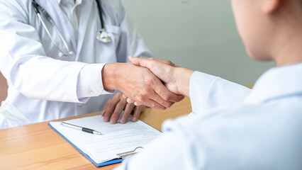 Male doctor shaking hands with female patient to congratulation after the treatment method successful