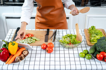 Top view of asian housewife holding ladle and touching touchscreen on tablet to researching new recipes