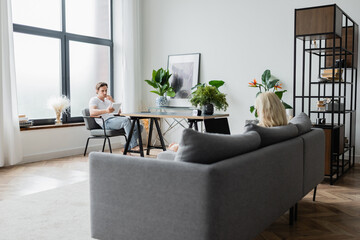 blonde woman using laptop with blank screen near boyfriend with digital tablet in living room