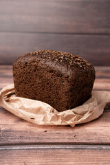 rye rectangular bread with cumin in paper packaging on a wooden table