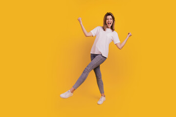 Fototapeta na wymiar Photo of excited funny carefree lady dance have fun wear casual t-shirt jeans sneakers on yellow background