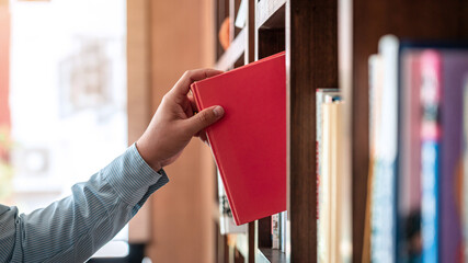 Close up of asian man checking interesting book from bookcase to searching a book and taking off...