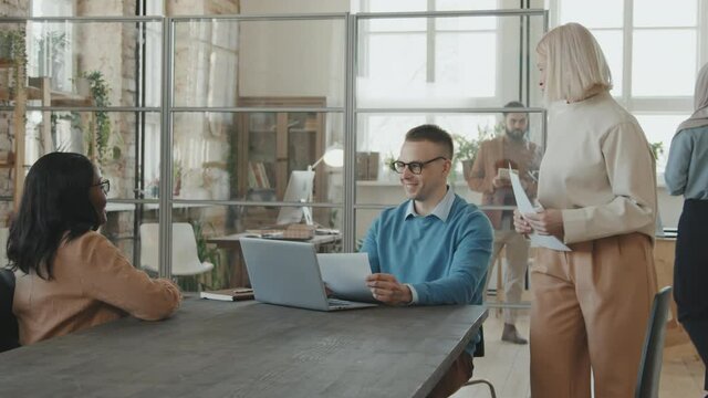 Tracking shot of cheerful male executive sitting at table in office and smiling as female HR manager and African-American female job candidate walking into conference room for job interview