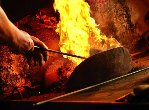 Detail of blacksmith s forge with strong flames. Mans Hands setting up fire in forge