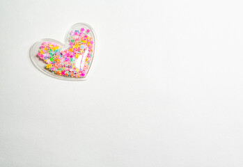 A plastic heart with colorful tiny stars inside isolated on a white background with free space for tex, top left.