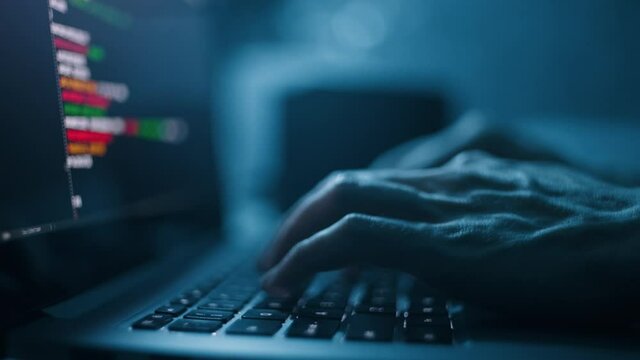 Programmer or computer hacker typing code on laptop keyboard. Closeup