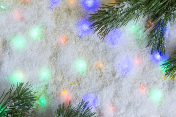 Obraz na płótnie Canvas Bright New Year background artificial snow and colored lights with fir branches place for text.