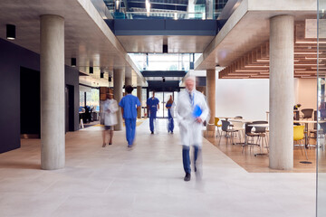 Medical Staff Walking Through Busy Hospital With Motion Blur