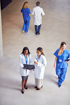 Overhead Shot Of Two Female Medical Staff In White Coats Discussing Patient Scan In Busy Hospital