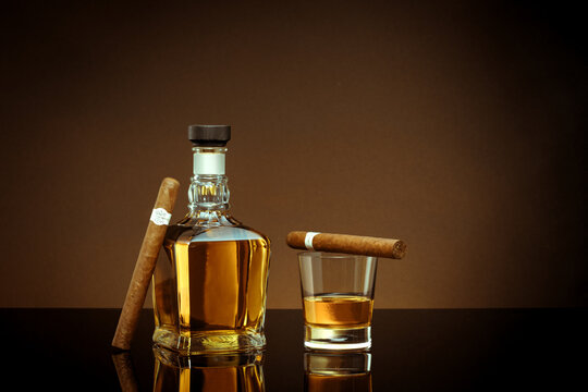 NO LOGOS OR TRADEMARKS!  SELF MADE LABELS!  close up view of cigar, bottle of cognac and a glass aside on color back. 