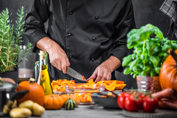 Chef cutting fresh and delicious pumkin and vegetables for cooking soup