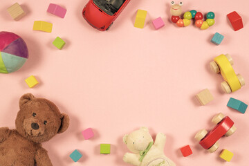 Baby kids toys frame with teddy bear, wooden toy car, colorful bricks on pastel background. Top view, flat lay