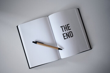Book with pen on desk with The end heading