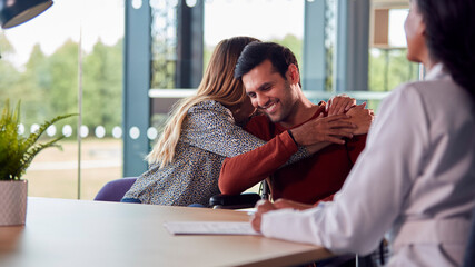 Woman Doctor Discussing Test Results With Smiling Couple n Hospital