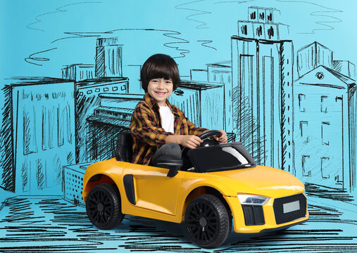 Cute little boy driving toy car and drawing of city on light blue background