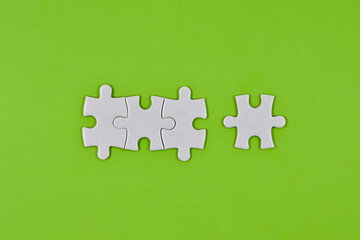 White puzzles pieces, order of priorities on a green paper background. Concept of communication and...
