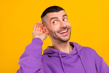 Photo of cute young brunet guy look empty space wear purple hoodie isolated on yellow color...