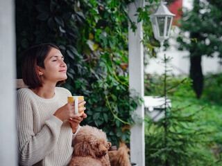 Young beautiful woman resting outdoors with cup of coffee with dog.