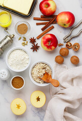 Ingredients for making apple desserts - ripe apples, wheat flour, oat flakes, butter, honey, walnuts, brown sugar and spices - cinnamon, anise, cardamom. Autumn baking. Selective focus, top view