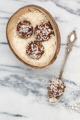 Raw homemade vegan chocolate coconut candy. Healthy food concept. useful dessert for gourmets. Raffaello. Marble background. Selective focus, top view, copy space
