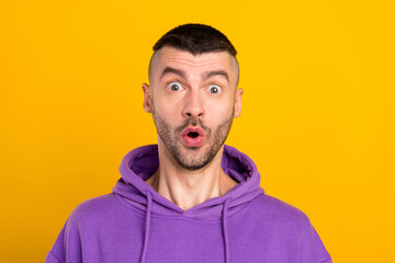 Photo of impressed young brunet guy wear violet hoodie isolated on yellow color background