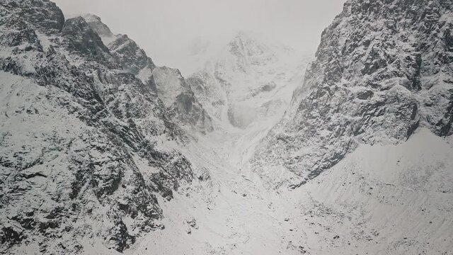 Storm, snowfall in the huge glacier of Mount Belukha, the valley of the Aktru River, the Altai Mountains. Cloudy weather, stone in the snow, storm, wildlife, winter forest, frozen mountain river in
