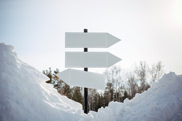 Empty white pointers, guidepost against winter nature background. Directional arrow signs on pole in snowy forest. Christmas and New Year concept.