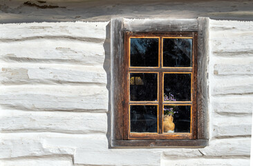 The window of a very old wooden house, painted white.