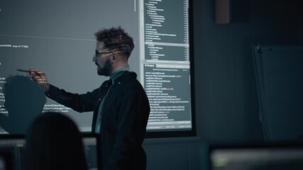 Teacher Giving Computer Science Lecture to Diverse Multiethnic Group of Female and Male Students in Dark College Room. Projecting Slideshow with Programming Code. Explaining Information Technology.