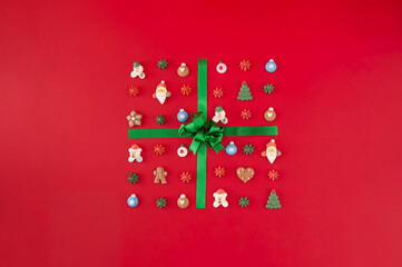 Gift box of cookies with green ribbon on the red background. Christmas holiday creative concept.