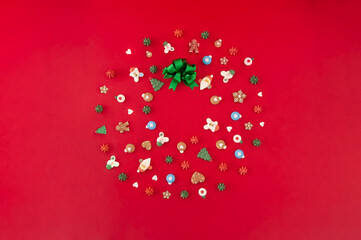 Christmas wreath of cookies with green ribbon on the red background. Christmas holiday creative concept.