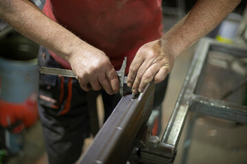 The worker works with metal. Construction tools, hands close-up. Work in the factory.