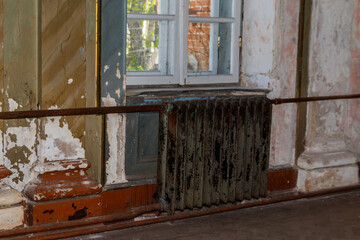 Old cast iron heating battery in a room of abandoned house