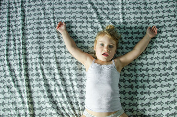 The little girl woke up in the morning and is lying on her blanket