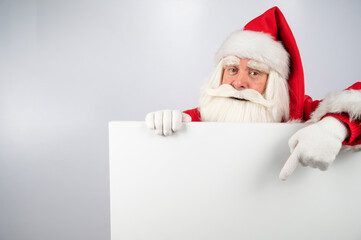 Naklejka premium Santa Claus points to an empty white space. Promotional offer for Christmas.